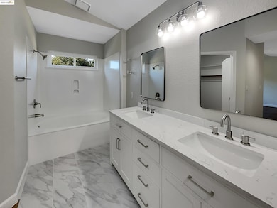 Bathroom featuring double vanity, shower / tub combination, lofted ceiling, and light marble finish floors