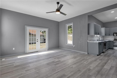 Dining room connected to kitchen with a textured wall, ceiling fan, french doors, healthy amount of natural light, and light wood-style floors