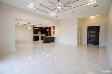 Unfurnished living room with a tray ceiling, ceiling fan, light marble finish flooring, and recessed lighting