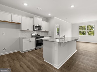 Aria kitchen off of the entry hallway with white cabinets with crown molding and hardware