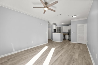 Unfurnished living room with crown molding, light wood finished floors, and ceiling fan