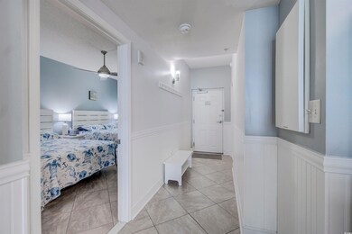 Hallway featuring wainscoting, light tile patterned floors, and a decorative wall