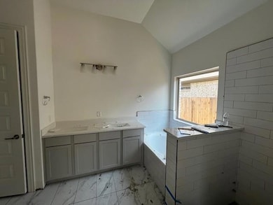 Full bath with marble look tile flooring, vaulted