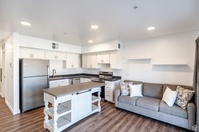 Kitchen featuring visible vents, open shelves, dark countertops, open floor plan, and appliances with stainless steel finishes