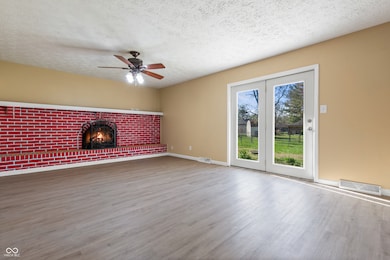 unfurnished living room featuring a fireplace, visible vents, ceiling fan, and wood finished floors