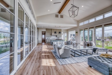 An entire wall of glass doors opens to the back terrace, flooding the space with natural light and blurring the lines between indoors and out. Just beyond, a charming kitchen garden awaits—an extension of the home’s thoughtful design, perfect for gathering herbs or enjoying a quiet moment among the greenery.
