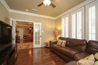 To the left of the entryway is a spacious study, currently being used as a TV room.  The same wonderful hardwoods, crown molding and plantation shutters give this room an elegant touch!