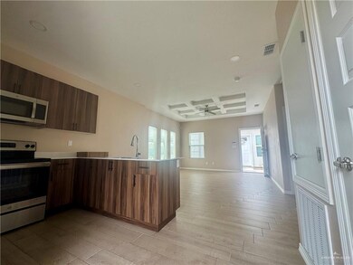 Kitchen featuring a ceiling fan, coffered ceiling, open floor plan, a peninsula, and appliances with stainless steel finishes