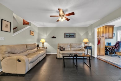 Living area with a ceiling fan, an office area, and baseboards