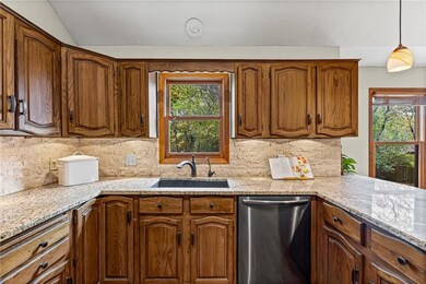 Kitchen with dishwasher, light stone counters, pendant lighting, brown cabinets, and tasteful backsplash