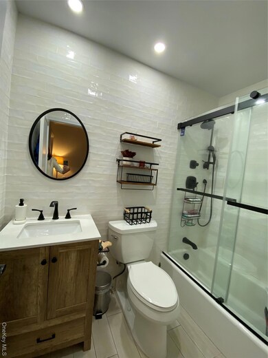 Bathroom featuring tile walls, vanity, shower / bath combination with glass door, and recessed lighting