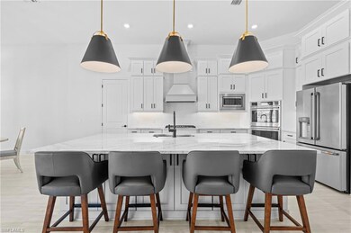 Kitchen featuring stainless steel appliances, white cabinetry, recessed lighting, light stone countertops, and pendant lighting