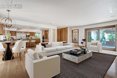 Living area featuring light wood-style floors, recessed lighting, and a chandelier, virtually staged