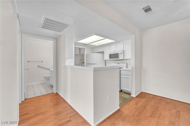 Kitchen featuring white cabinets, tile countertops, white appliances, light wood-style floors, and a peninsula