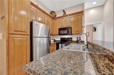 Kitchen featuring black appliances, a sink, and dark countertops