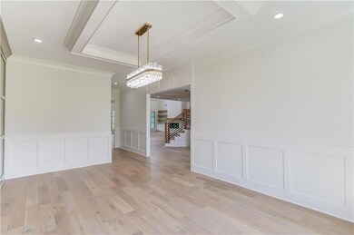 Empty room with light hardwood / wood-style flooring, a notable chandelier, and a raised ceiling