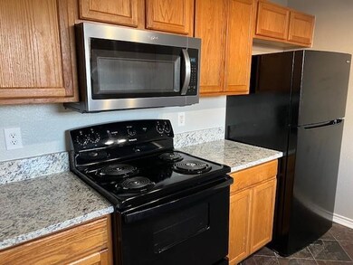 Kitchen with black appliances and light stone coun
