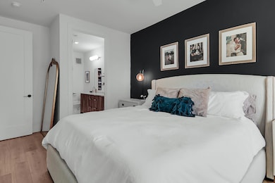 Bedroom with wood finished floors, connected bathroom, and recessed lighting
