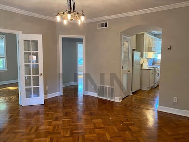 Unfurnished dining area with arched walkways, crown molding, and a chandelier