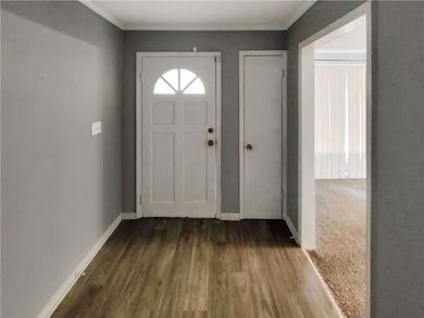 Foyer entrance with dark wood-type flooring and ornamental molding
