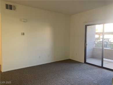 Empty room featuring dark colored carpet and baseboards