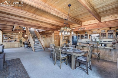 Dining area featuring wooden walls, beamed ceiling, stairs, wood ceiling, and a chandelier