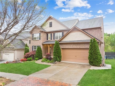 View of front of home with brick siding, a front yard, an attached garage, and driveway