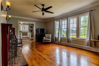 Unfurnished living room with healthy amount of natural light, hardwood / wood-style flooring, crown molding, and a ceiling fan