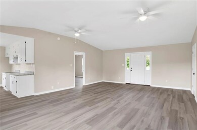 Unfurnished living room featuring ceiling fan, lofted ceiling, light wood-type flooring, and baseboards
