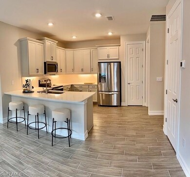 Kitchen featuring appliances with stainless steel finishes, tile floors, a kitchen breakfast bar,  and recessed lighting