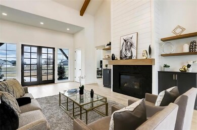 Living room featuring recessed lighting, a high ceiling, beam ceiling, light wood-style floors, and a glass covered fireplace