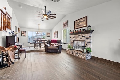 Living room with wood finished floors, a ceiling fan, plenty of natural light, vaulted ceiling, and a fireplace