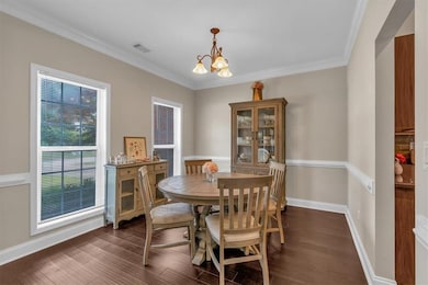 Dining area featuring a chandelier, dark wood-style floors, crown molding, and baseboards