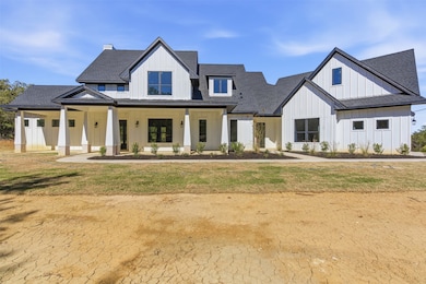 Modern inspired farmhouse with board and batten siding, a shingled roof, covered porch, and a front lawn