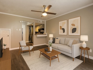 Living room with stacked washer / drying machine, dark wood finished floors, ornamental molding, a textured ceiling, and a ceiling fan