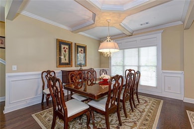 Dining space with wainscoting, coffered ceiling, crown molding, dark wood-style flooring, and beam ceiling