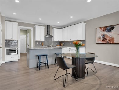 Kitchen featuring wall chimney range hood, a kitch