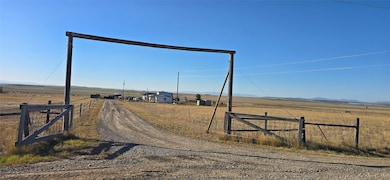 View of dirt / gravel road with a view of rural / pastoral area, a gated entry, and a mountain view