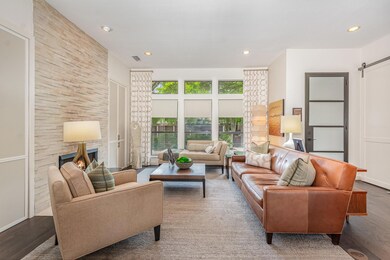 Living room with a barn door, a stone fireplace, w