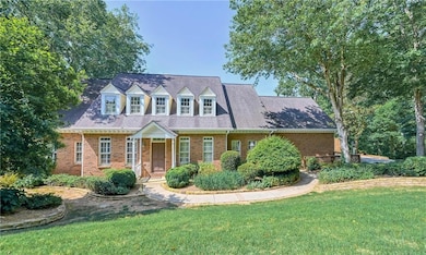 Cape cod home featuring a front yard, brick siding, and a shingled roof
