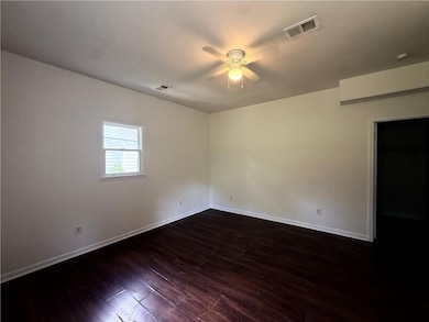 Spare room featuring ceiling fan, baseboards, and dark wood-style floors