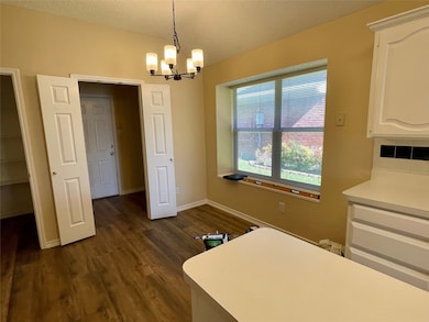 Dining space featuring dark wood-type flooring, a chandelier, and a textured ceiling