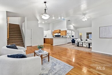 Living room featuring light wood finished floors, stairway, a ceiling fan, and high vaulted ceiling