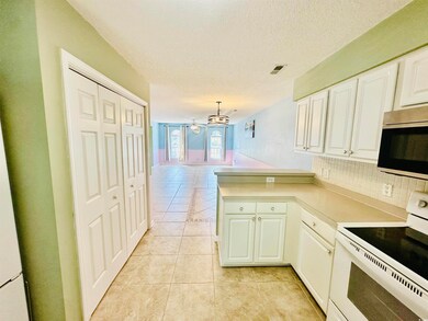 Kitchen featuring electric range, stainless steel microwave, a peninsula, light tile patterned floors, and a chandelier