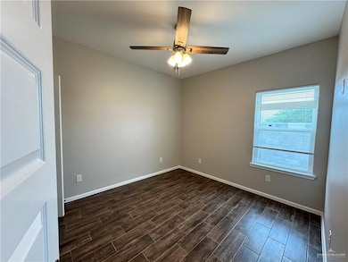 Unfurnished room with dark wood finished floors, a ceiling fan, and baseboards