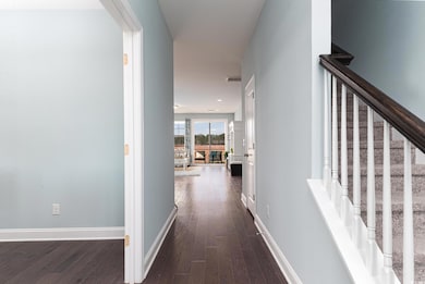 Corridor with dark wood finished floors, stairway, and baseboards