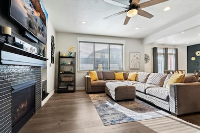 Living room with a tiled fireplace, a textured ceiling, hardwood / wood-style flooring, recessed lighting, and ceiling fan