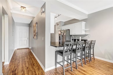 Kitchen with kitchen peninsula, light hardwood / wood-style flooring, white cabinets, and stainless steel fridge with ice dispenser