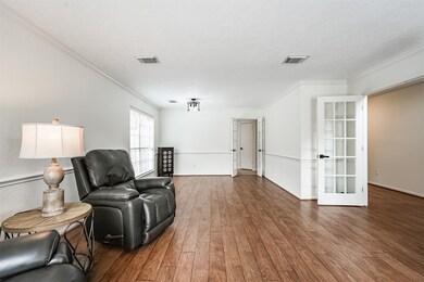 Looking the opposite direction in the formal living and dining room, note the side-facing window, the updated industrial-style light in the dining area, and the second set of French doors that allow for direct kitchen access.