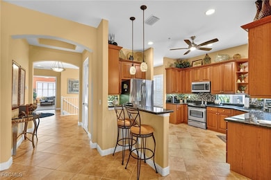 Kitchen with open shelves, arched walkways, backsplash, a breakfast bar area, and hanging light fixtures